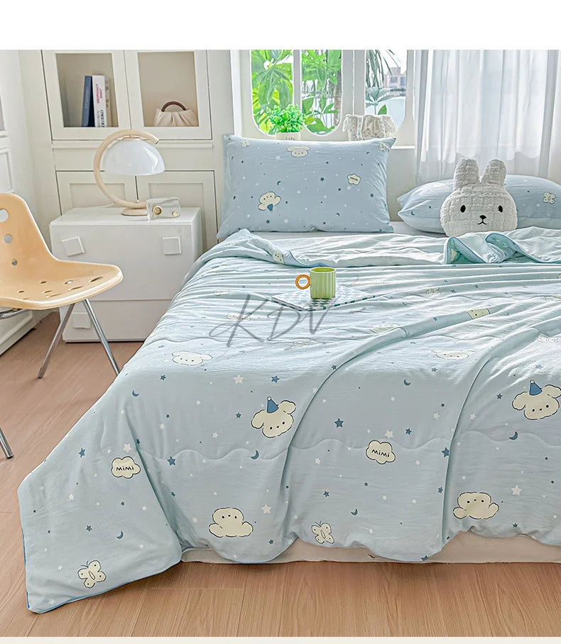 A light blue quilt blanket with a white pattern of clouds and stars is displayed on a bed in a bright room.
