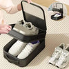 A black portable travel shoe organizer bag is shown open, displaying a pair of white sneakers.