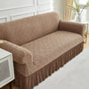A tan jacquard stretch sofa cover featuring a geometric woven pattern on a beige sofa.