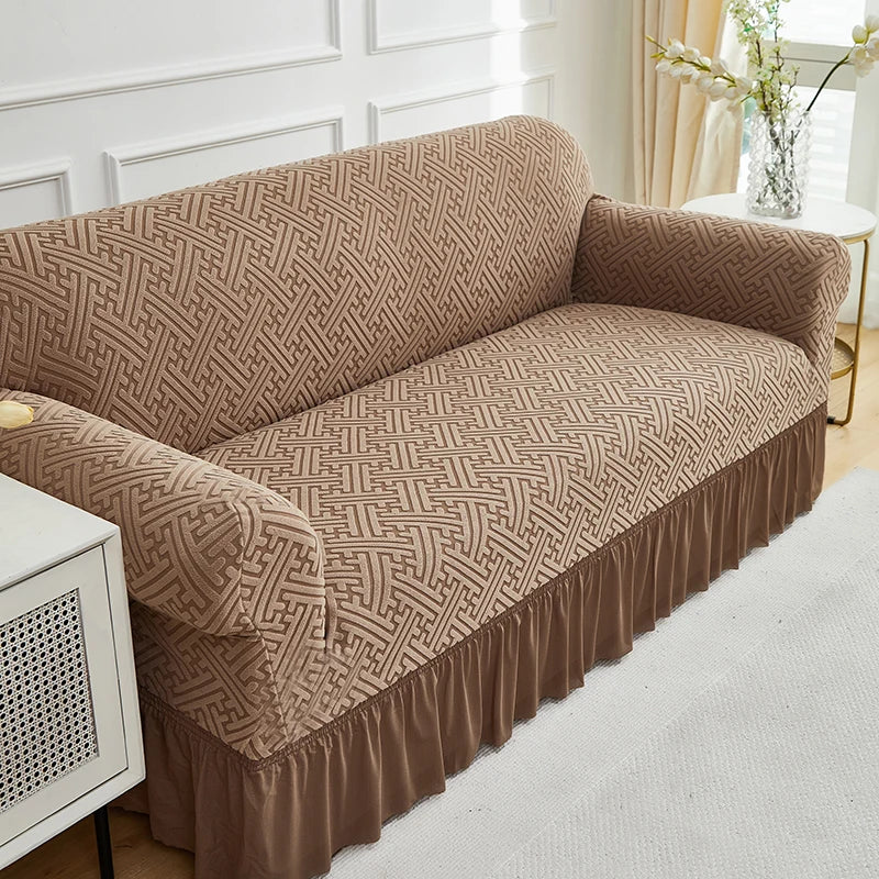 A tan jacquard stretch sofa cover featuring a geometric woven pattern on a beige sofa.
