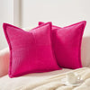 A bright pink striped corduroy lumbar support pillow cushion resting on a light-colored fabric.