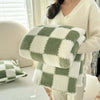 A soft flannel panda fleece blanket in green and white checkered pattern being held by a person.