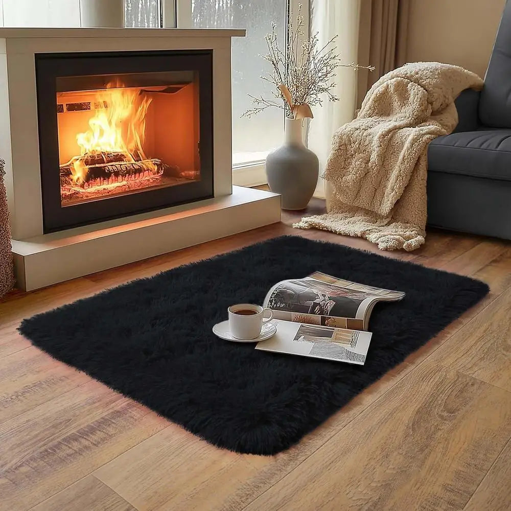 A plush solid black area rug placed on a wooden floor in a living room setting.