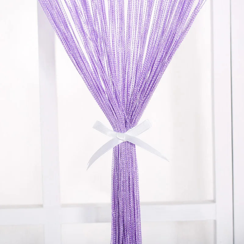 A purple thread curtain tie-back with a white ribbon tied at the top.