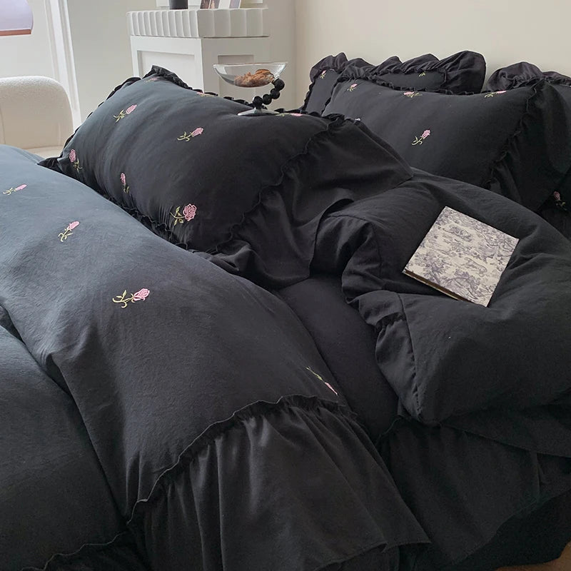 A black embroidered rose duvet cover set displayed on a bed.