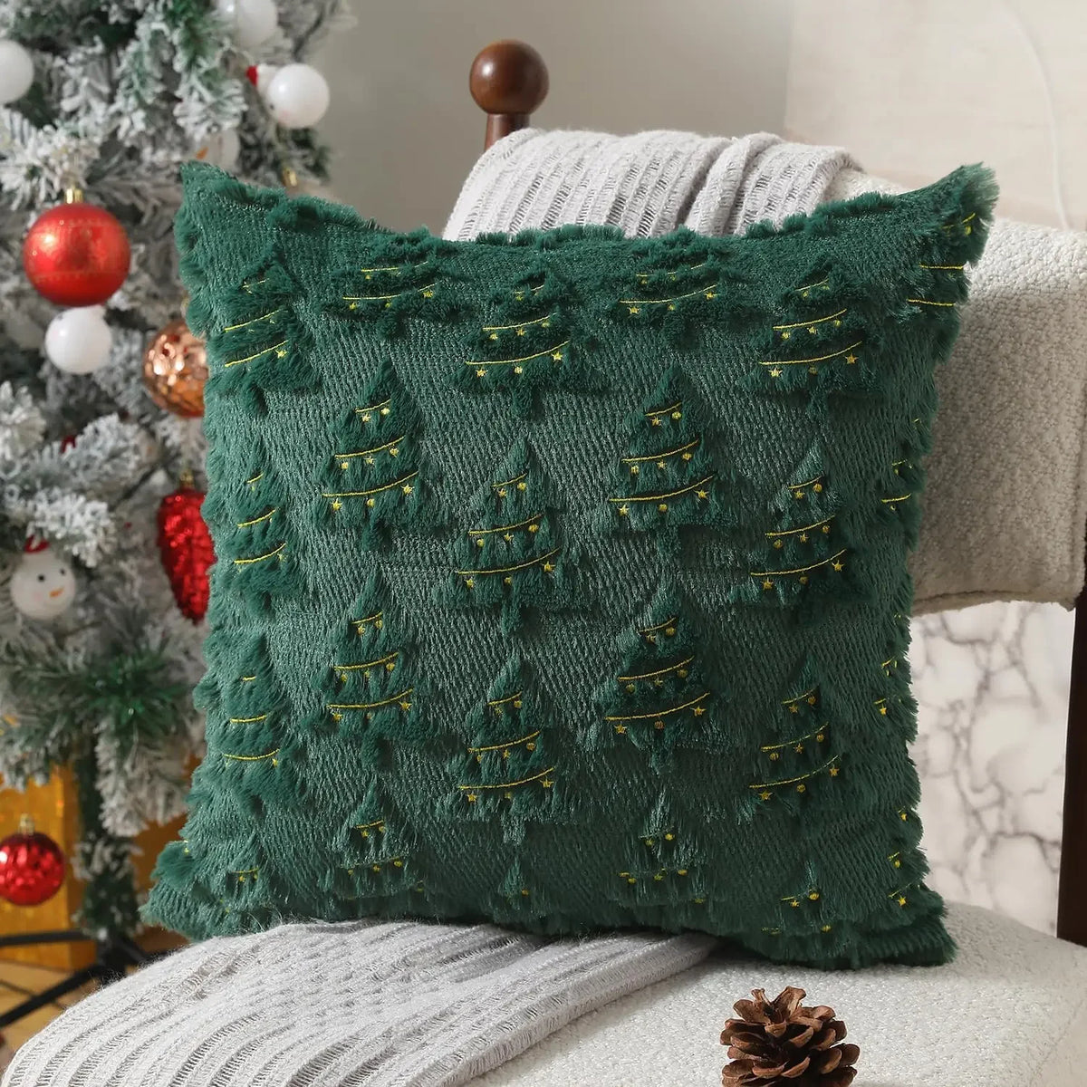 A dark green textured corduroy throw pillow with gold embroidered Christmas tree designs