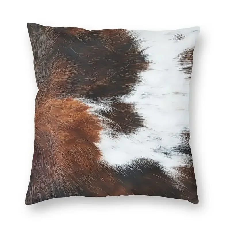 A square cushion cover made of faux fur cowhide print featuring brown and white patches.