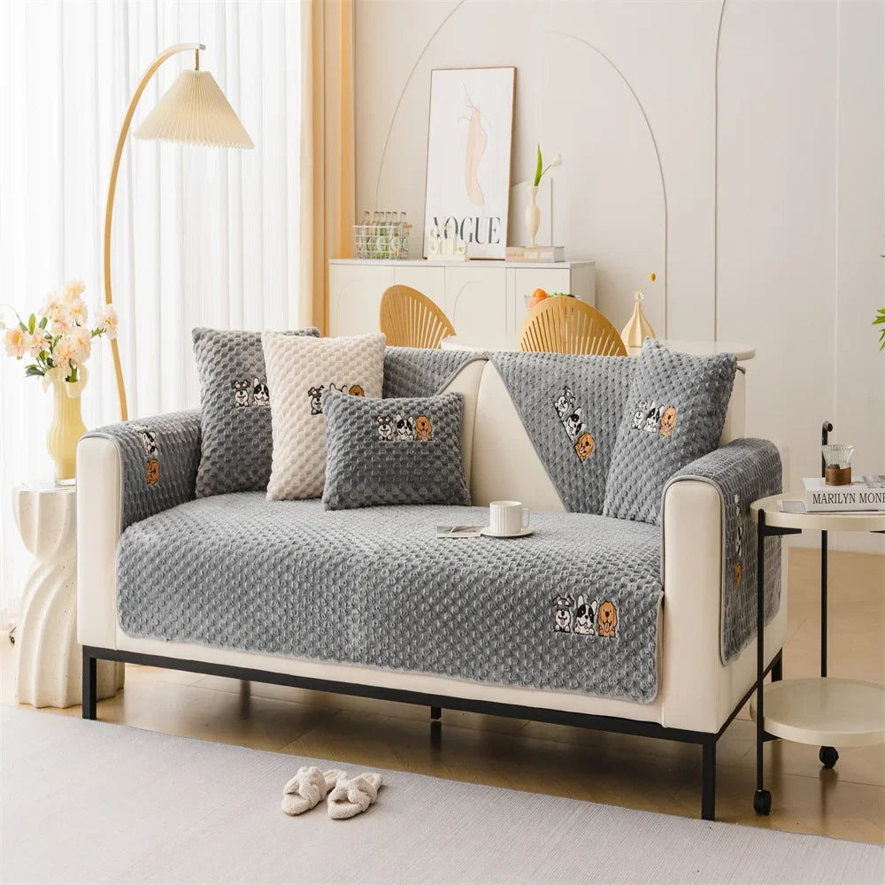 A beige sofa covered with a gray non-slip plush fabric featuring decorative animal patterns.