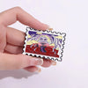 A hand holds a vintage enamel airline ticket lapel pin featuring a stylized monster design.