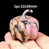 A pink and black marbled natural stone pumpkin figurine with a silver stem is held in a hand.