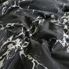 Dark gray fabric with white marble print pattern draped in soft folds.