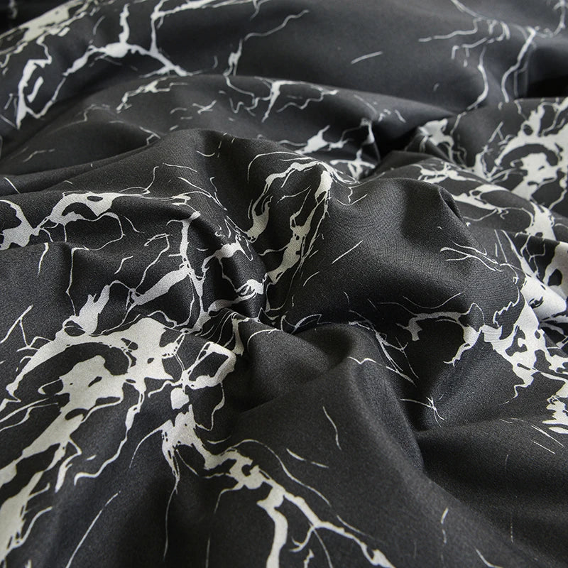 Dark gray fabric with white marble print pattern draped in soft folds.