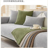 A sofa is covered with a layered, textured green and gray fabric protection cover.