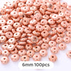 A pile of rose gold colored geometric acrylic beads for jewelry making