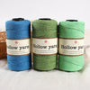 A set of three spools of hollow yarn in blue, green, and light green for knitting and crochet projects.