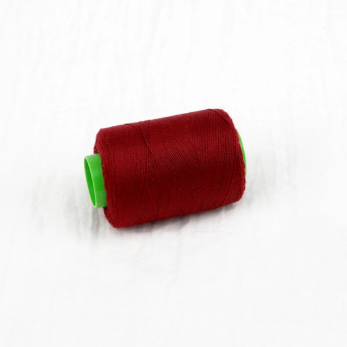 A roll of deep red sewing thread with a green core.