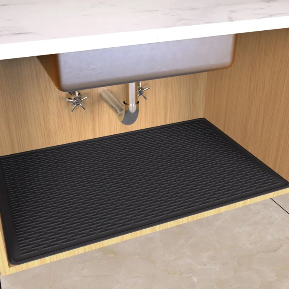 A black silicone mat liner is placed inside a wooden under sink cabinet for waterproofing.