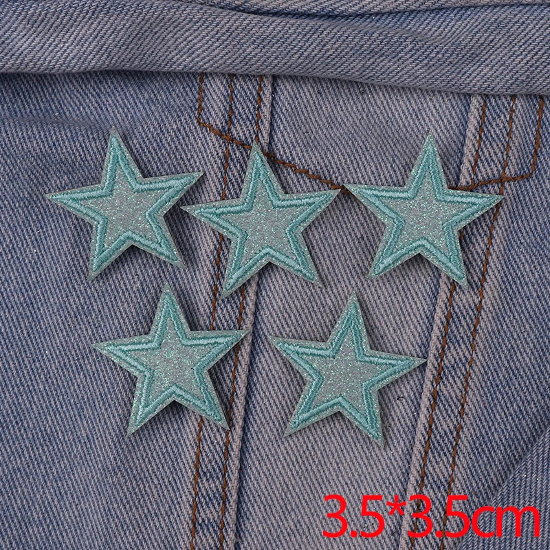 Five glitter iron-on embroidered star patches sewn onto a denim fabric.