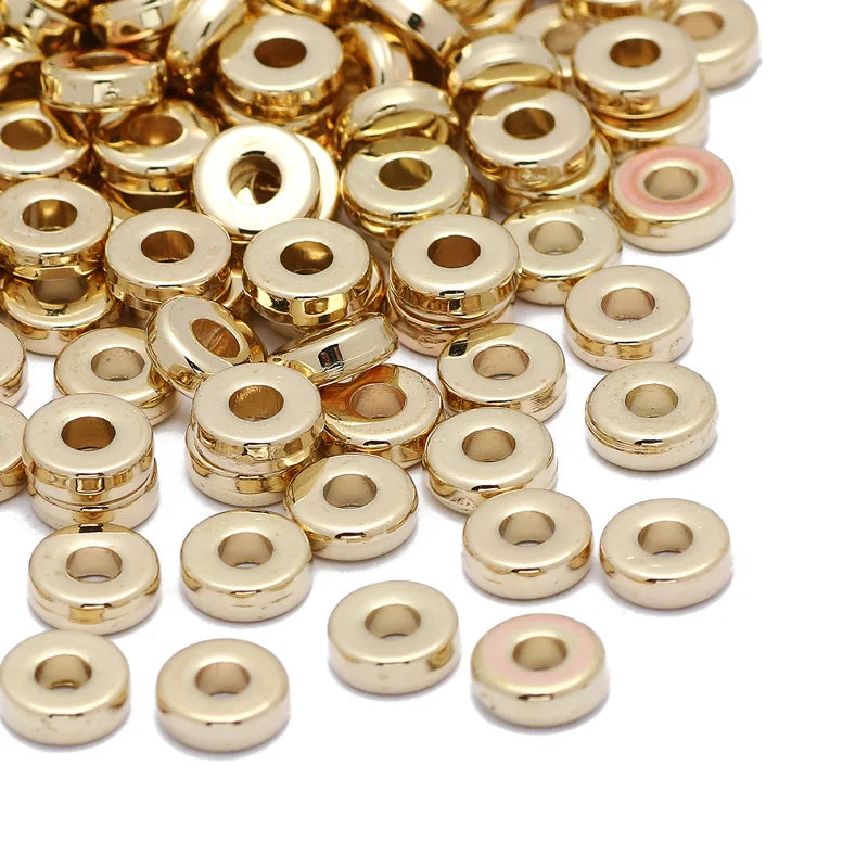 A pile of small, round, gold-colored acrylic flat spacer beads for DIY jewelry.