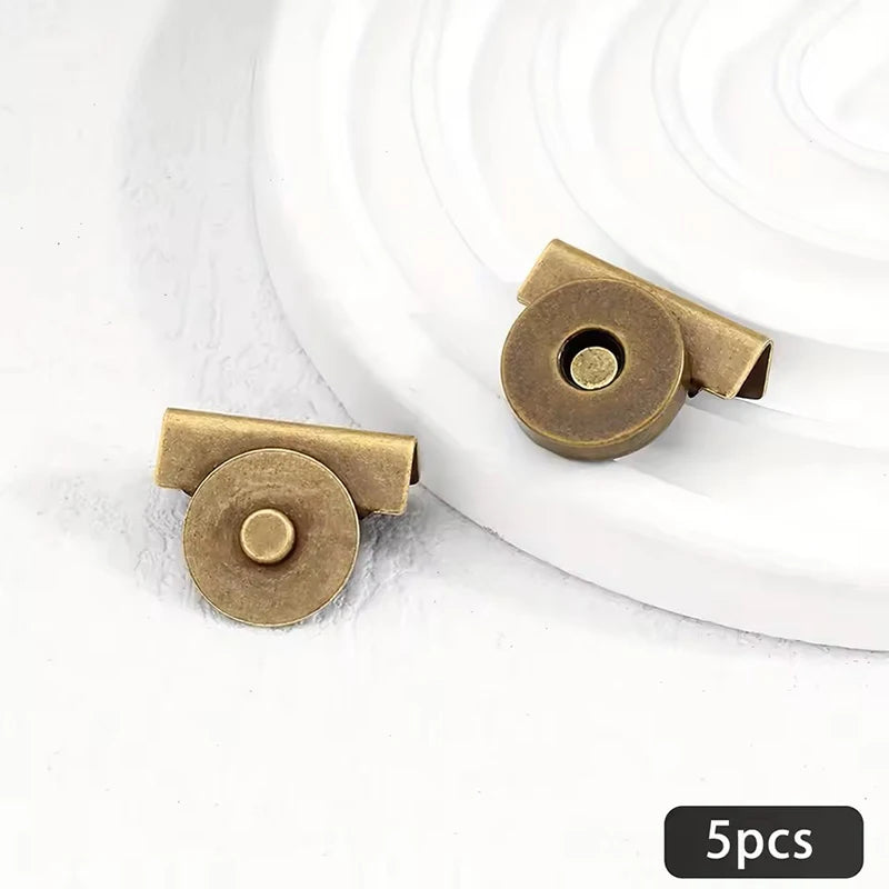 Five brass metal seamless magnetic closure buckles arranged on a white surface.