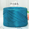 A spool of metallic teal cake yarn used for crafting.
