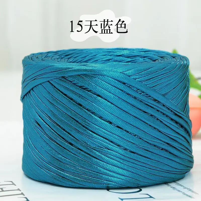 A spool of metallic teal cake yarn used for crafting.