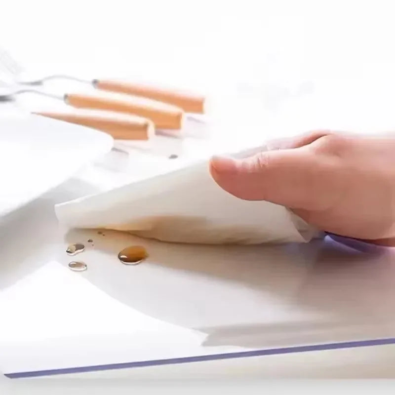 A hand is placing a white mat onto a clear plastic table protector mat.