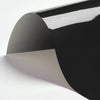 A sheet of black heat transfer vinyl being applied to a white surface at an angle.
