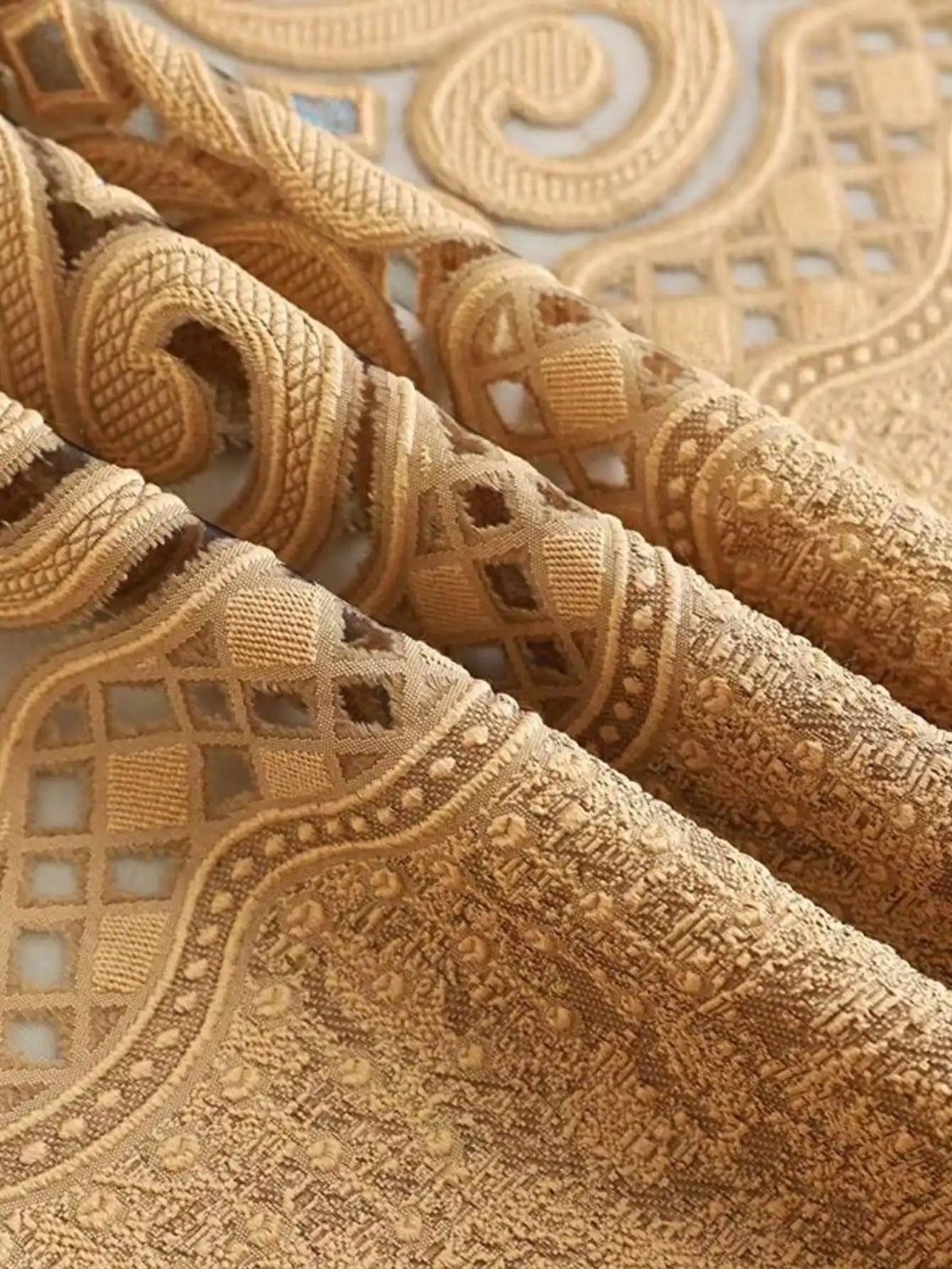 Close-up of a beige hollow perforated curtain fabric with intricate lace and embroidered detailing.