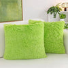Two bright lime green faux fur throw pillows resting on a white sofa next to a potted plant.