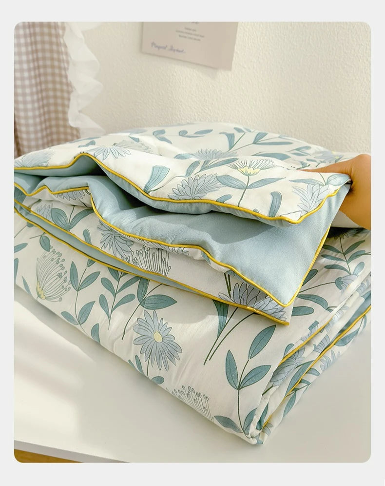 A stack of light blue and white patterned Summer Gauze Cotton Quilt bedding.
