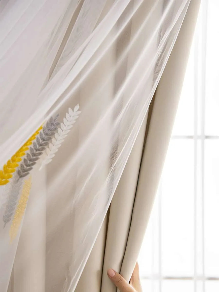A sheer beige curtain with embroidered wheat stalks in yellow and gray, shown partially drawn.