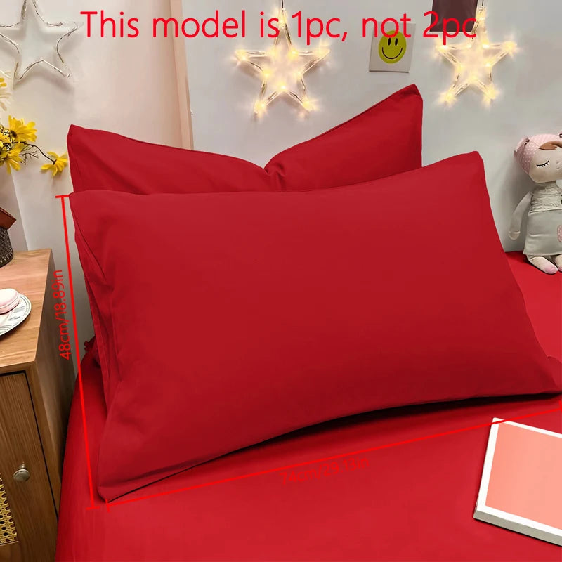 A bright red matte solid color pillowcase is shown on a bed with decorative star lights in the background.