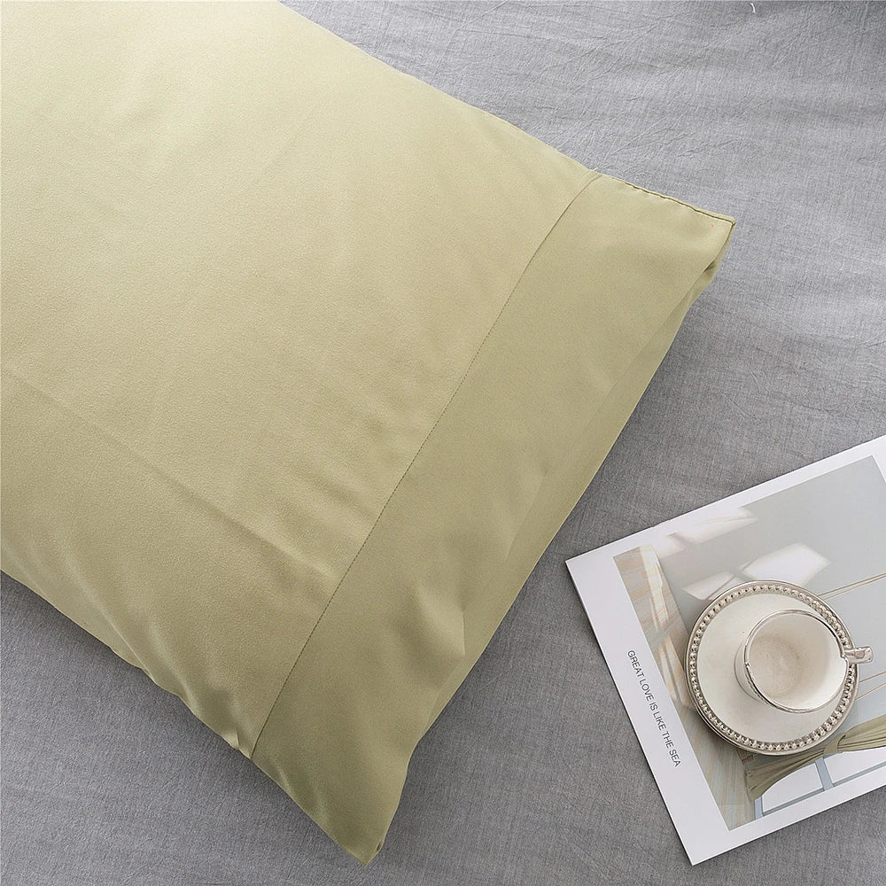 A light olive green microfiber pillow cover is shown on a gray fabric surface.