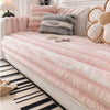 Pink and gray plush velvet sofa protector covers with decorative pillows on a light-colored bed.