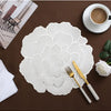 White gold plated peony coasters with delicate embossed floral patterns placed on a brown surface next to a cup and fork.