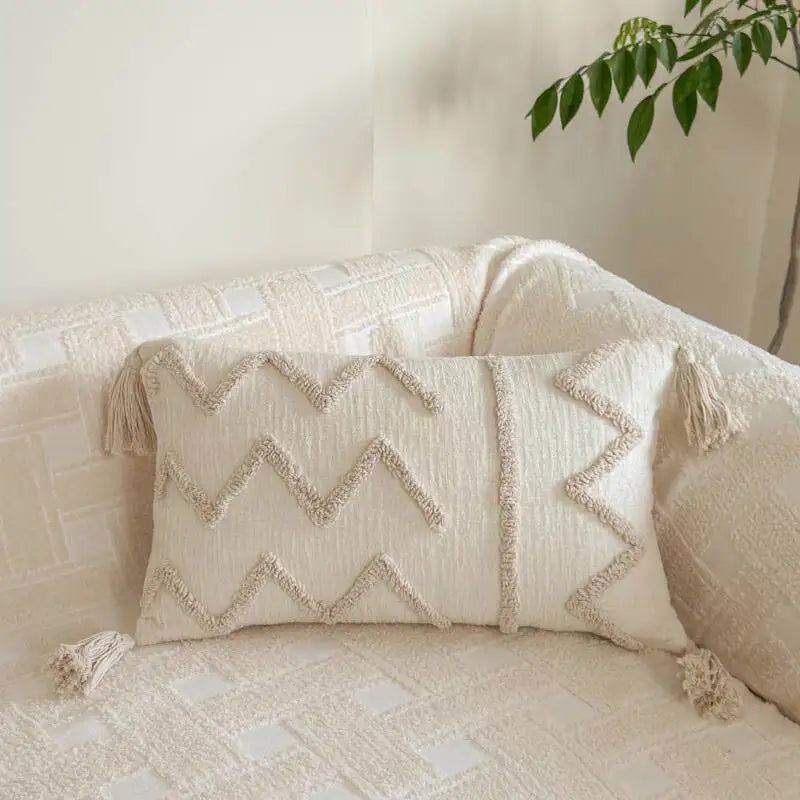 A cream knit pillow cover with a chevron pattern resting on a light-colored sofa.