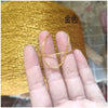 A hand holds a strand of gold metallic yarn used for crochet and knitting.