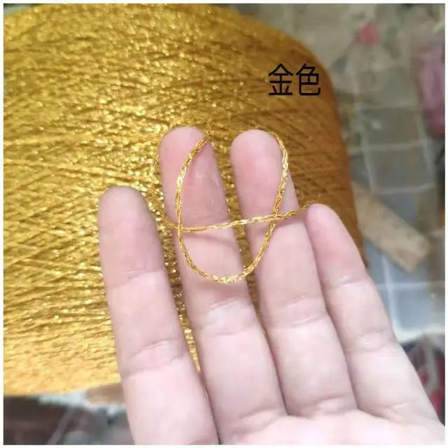 A hand holds a strand of gold metallic yarn used for crochet and knitting.