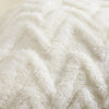 Close-up of a white jacquard plush throw pillow cover with a geometric textured pattern.