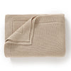 A beige knitted baby swaddle blanket folded and displayed on a white background.