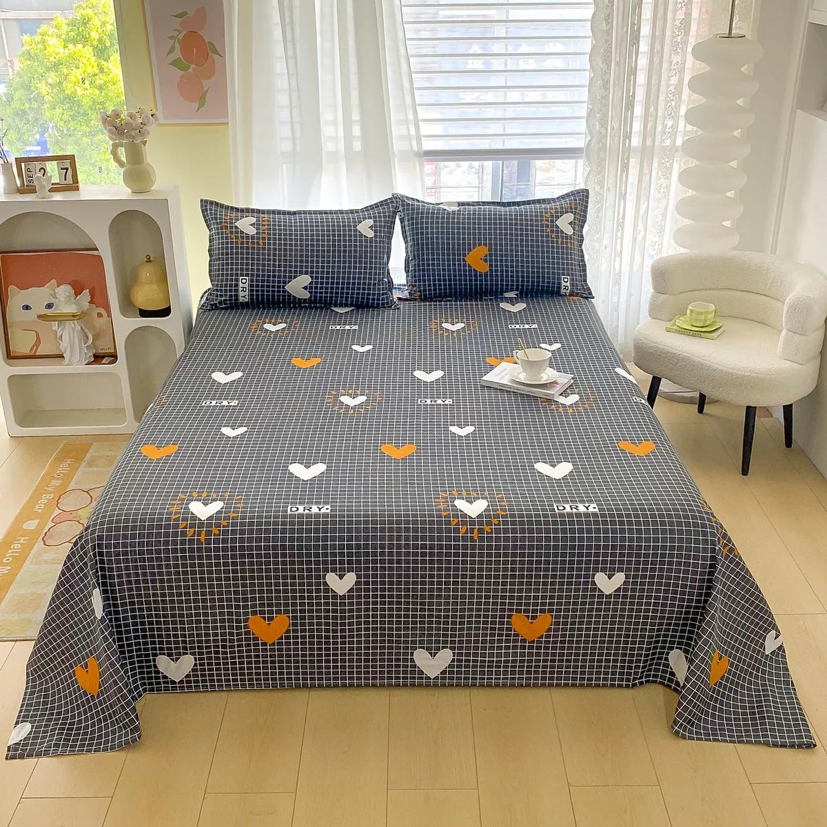 A flat bed with dark gray and orange floral print sheets displayed in a bright bedroom.