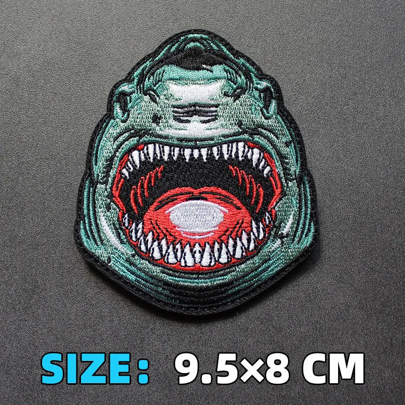 An embroidered patch depicting an angry, snarling face with green and red details.