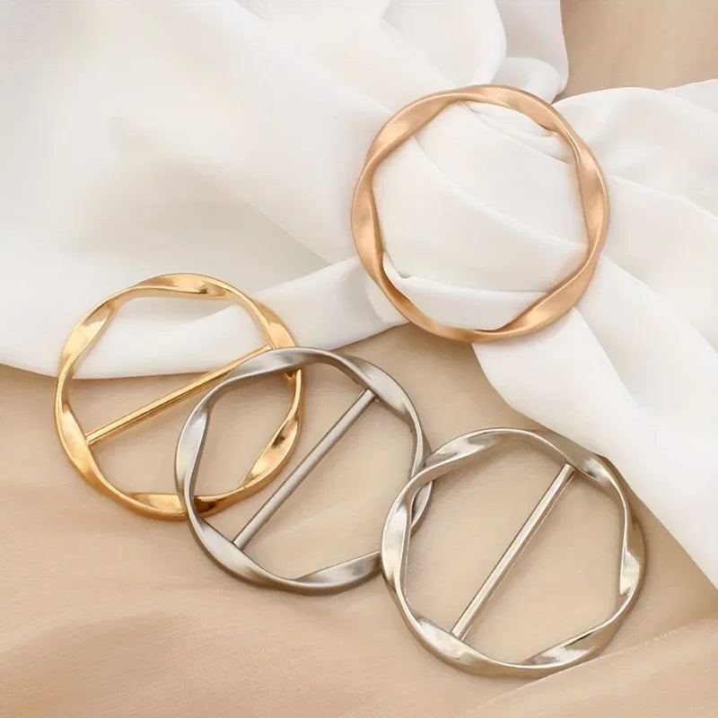 A collection of gold and silver metal round clip buckles displayed on a soft fabric background.