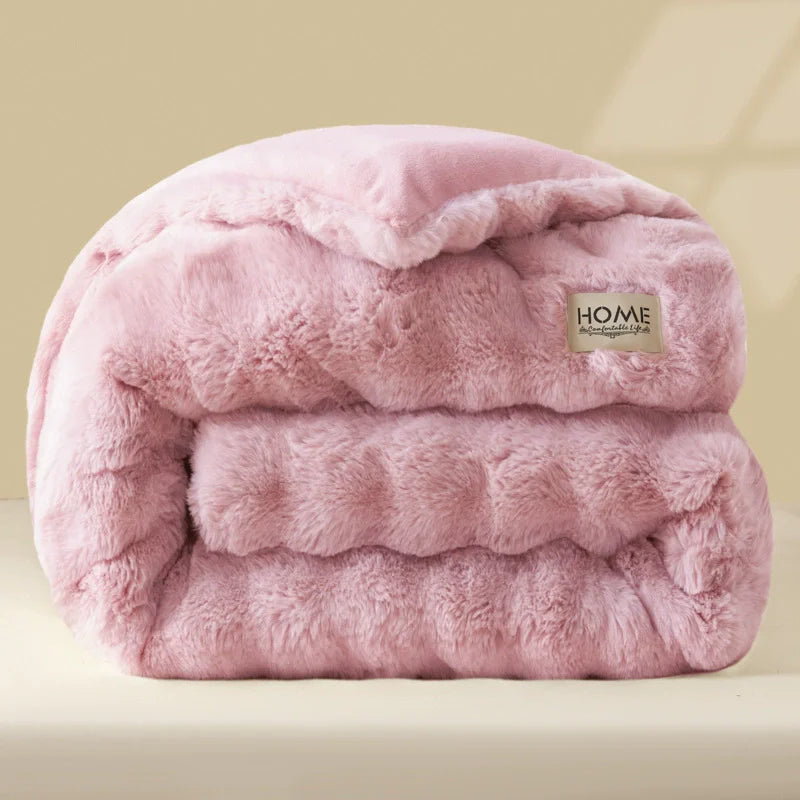 A pink ultra-warm plush rabbit quilt comforter folded and displayed on a light surface.