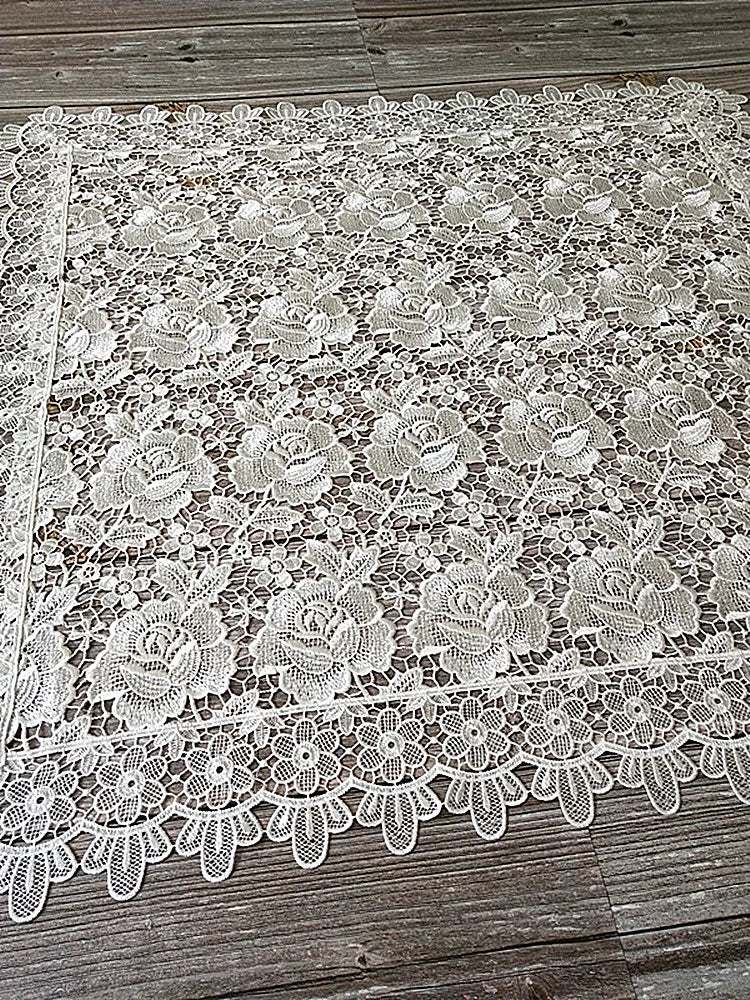 White floral lace tablecloth with scalloped edge on a wooden surface.