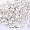 A pile of small silver-colored geometric acrylic beads for jewelry making
