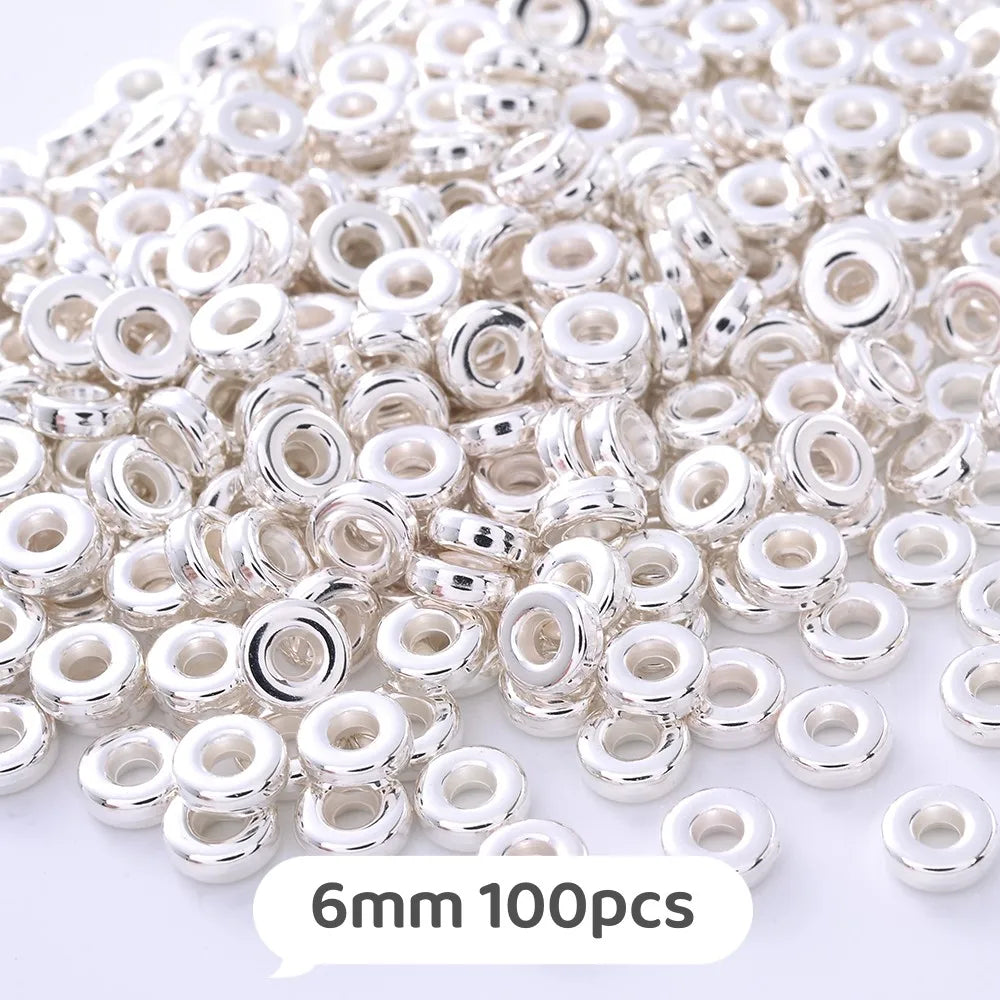 A pile of small silver-colored geometric acrylic beads for jewelry making