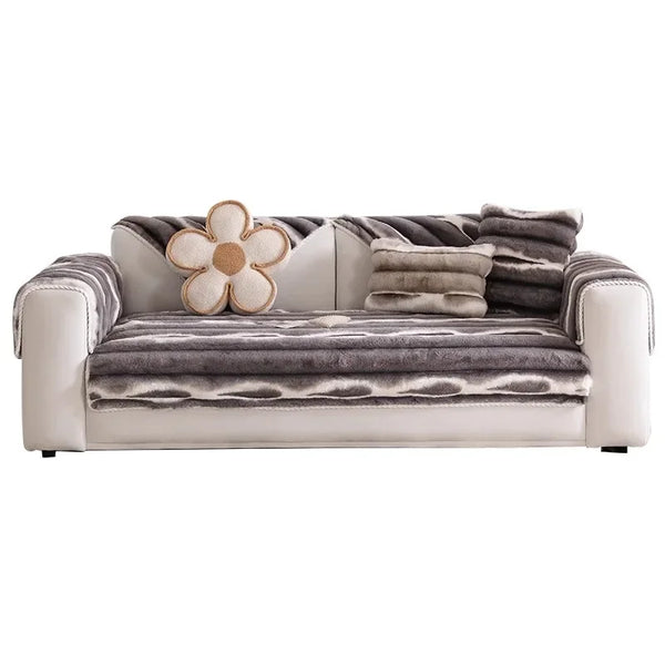 A plush sofa cover in gray stripes featuring a large, light-colored flower accent.