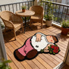 A funny cartoon rug depicting a man in pink pants and a white shirt with a red rose, placed on a wooden deck.